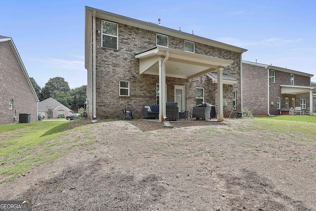 back of house with an outdoor hangout area, a yard, brick siding, and central AC