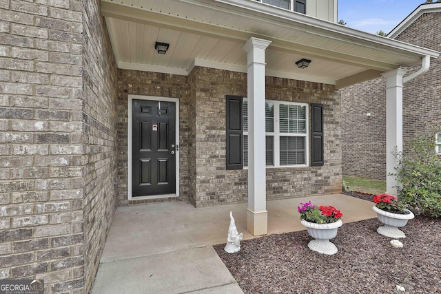 entrance to property with covered porch and brick siding