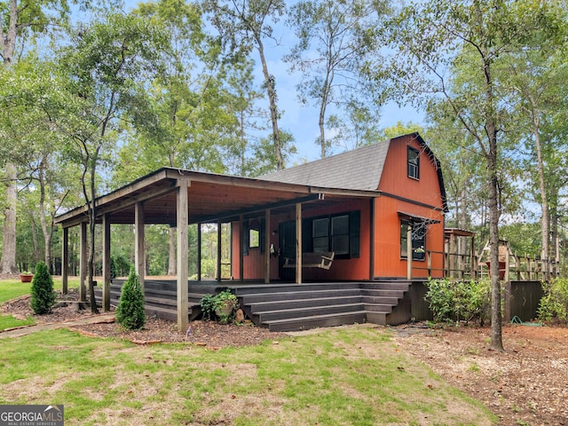 view of front of house with covered porch, a shingled roof, a front yard, and a gambrel roof