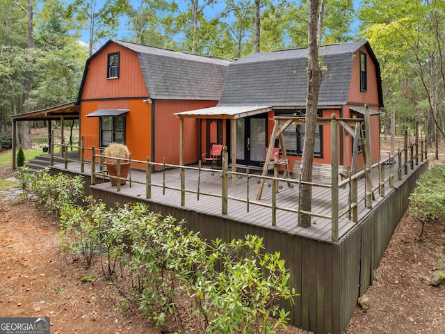 rear view of property with a shingled roof and a gambrel roof