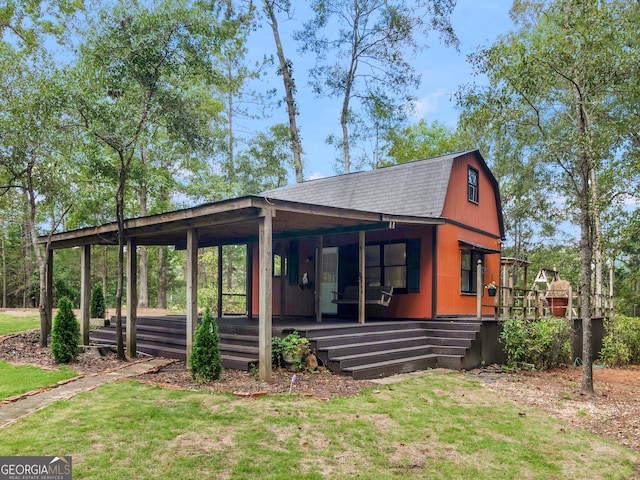 view of front of property featuring a porch, a front yard, a shingled roof, and a gambrel roof