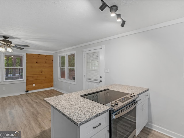 kitchen with light stone counters, stainless steel electric range oven, white cabinets, a textured ceiling, and light wood-type flooring