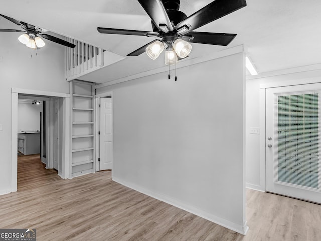 unfurnished living room featuring a ceiling fan, light wood-style flooring, and baseboards