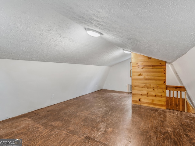 bonus room featuring radiator, a textured ceiling, vaulted ceiling, and wood finished floors