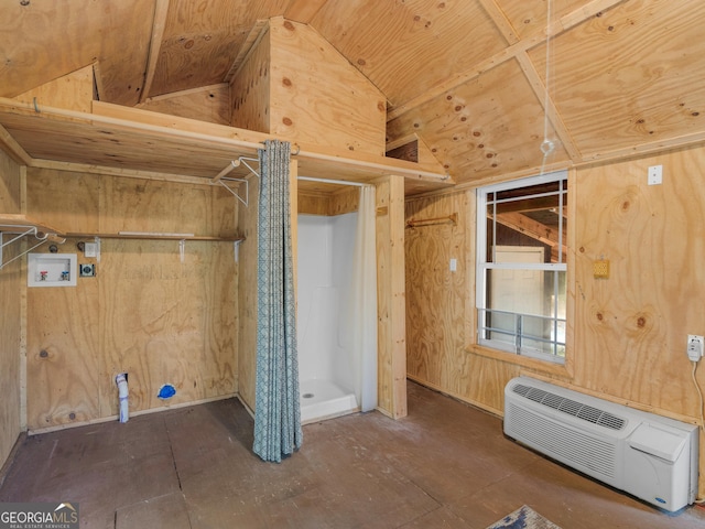 interior space with washer hookup, laundry area, a wall unit AC, and wood walls