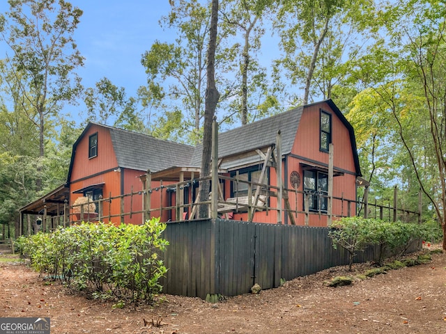 view of home's exterior with an outbuilding, roof with shingles, a barn, and a gambrel roof