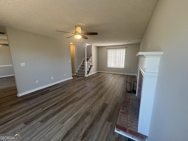 unfurnished living room with baseboards, a ceiling fan, dark wood-style flooring, stairs, and a fireplace