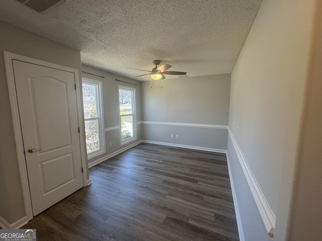 unfurnished room featuring dark wood-style floors, visible vents, ceiling fan, a textured ceiling, and baseboards