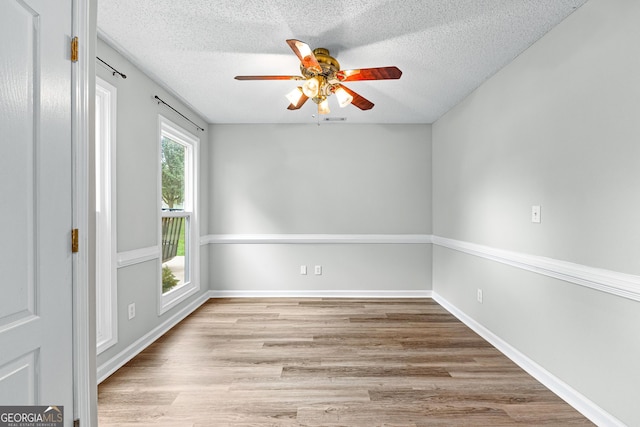 unfurnished room with a ceiling fan, a textured ceiling, baseboards, and wood finished floors