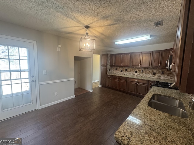 kitchen featuring dark wood-style floors, backsplash, a sink, and light stone countertops