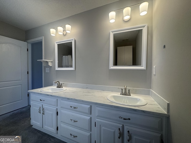 full bath featuring a sink, a textured ceiling, and double vanity