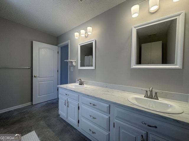 bathroom featuring a sink, a textured ceiling, baseboards, and double vanity