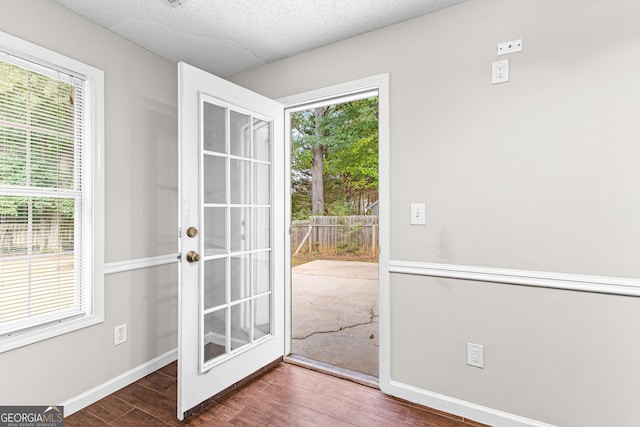 doorway to outside featuring plenty of natural light, a textured ceiling, baseboards, and wood finished floors