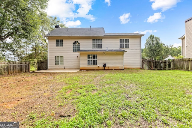 rear view of property featuring a yard, a patio area, and a fenced backyard