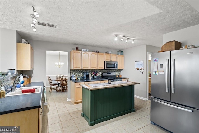 kitchen with a sink, appliances with stainless steel finishes, decorative backsplash, a center island, and light brown cabinetry