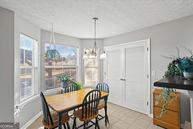 dining area featuring light tile patterned floors, a textured ceiling, baseboards, and an inviting chandelier