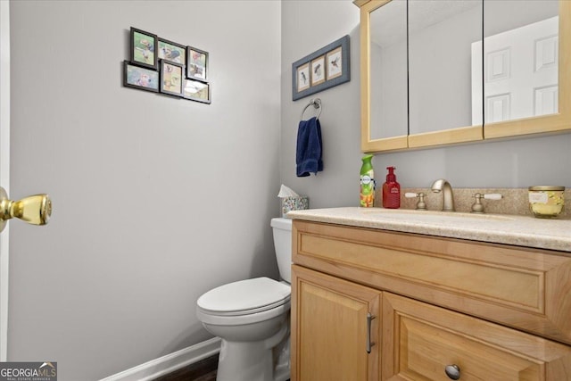 half bath featuring vanity, toilet, and baseboards