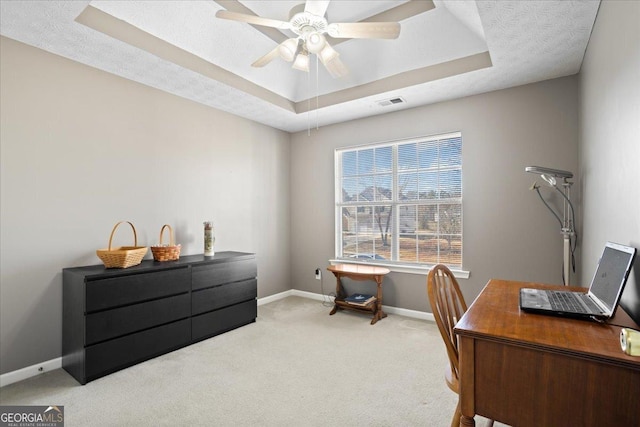 office area featuring ceiling fan, visible vents, baseboards, carpet, and a raised ceiling