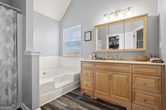 full bathroom featuring a shower with curtain, wood finished floors, a garden tub, vaulted ceiling, and vanity