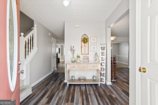 entryway with a textured ceiling, stairway, dark wood-style flooring, and baseboards