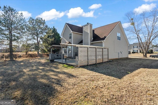 rear view of house featuring a patio, a chimney, and a lawn