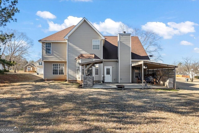 rear view of property featuring a patio area, a chimney, and a lawn