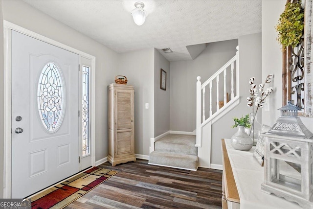 foyer featuring stairway, dark wood finished floors, visible vents, and a healthy amount of sunlight