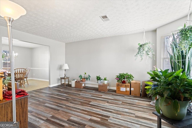 sitting room with baseboards, a textured ceiling, visible vents, and wood finished floors