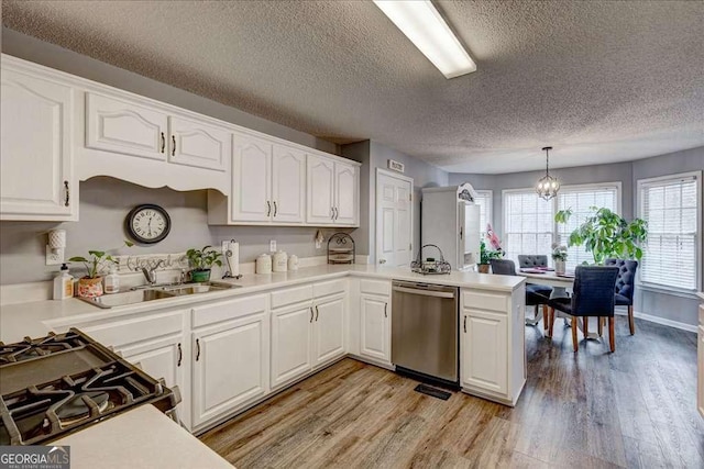 kitchen with a peninsula, stainless steel dishwasher, a sink, and light wood-style flooring