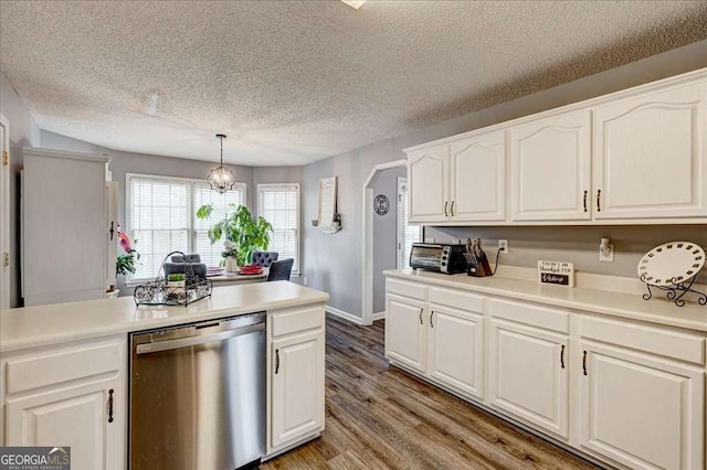 kitchen with light wood-style flooring, white cabinetry, light countertops, stainless steel dishwasher, and hanging light fixtures