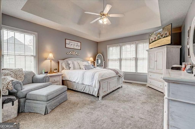 bedroom featuring carpet floors, a raised ceiling, ceiling fan, and baseboards