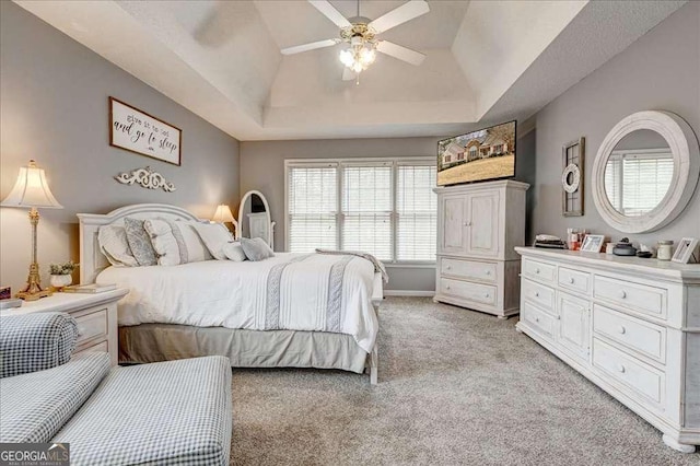 bedroom with light carpet, a tray ceiling, lofted ceiling, and a ceiling fan