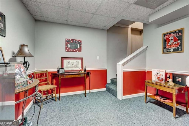 living area with stairs, a drop ceiling, carpet, and baseboards