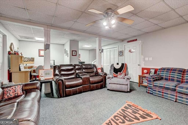 living area with a paneled ceiling, carpet, and a ceiling fan