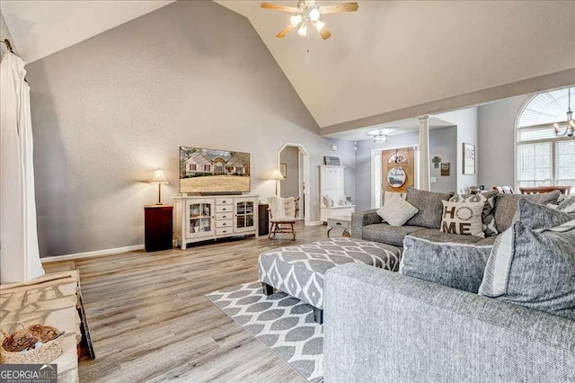 living area featuring arched walkways, light wood-style floors, ceiling fan, high vaulted ceiling, and baseboards