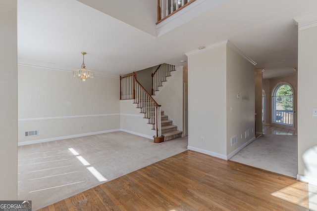 interior space featuring wood finished floors, visible vents, baseboards, ornamental molding, and stairway