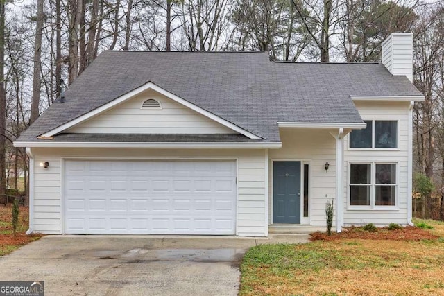 view of front facade with a shingled roof, driveway, a chimney, and an attached garage