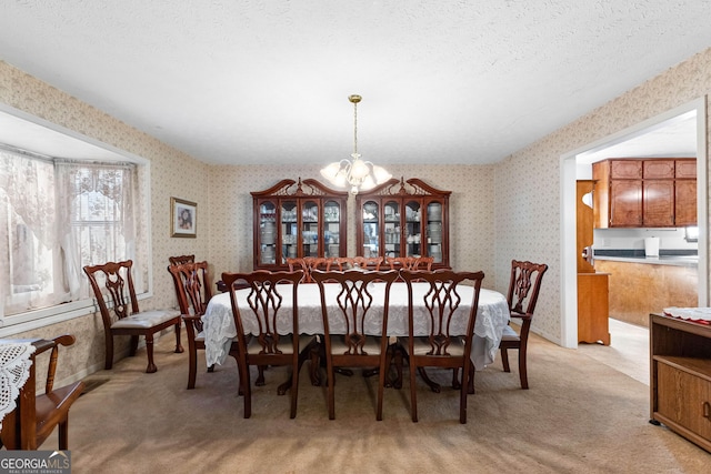 dining area with light carpet, a notable chandelier, a textured ceiling, and wallpapered walls