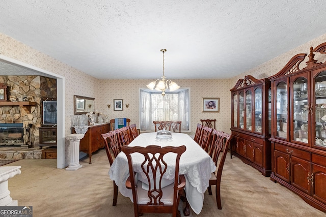 dining area with wallpapered walls, a fireplace, a textured ceiling, and light colored carpet