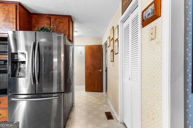 kitchen featuring visible vents, stainless steel refrigerator with ice dispenser, light floors, and wallpapered walls