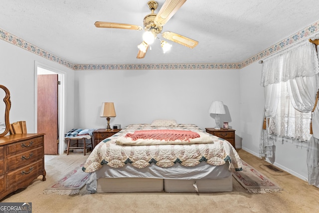 bedroom featuring a textured ceiling, ceiling fan, baseboards, and light colored carpet