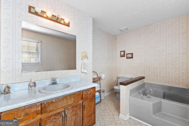 bathroom featuring a bath, wallpapered walls, a textured ceiling, and vanity