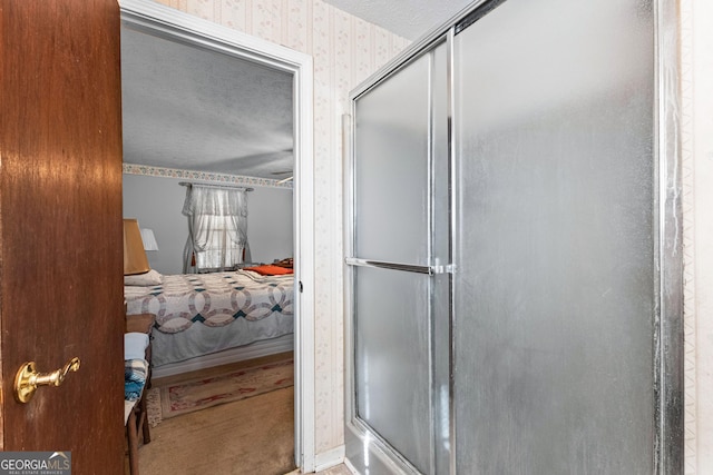 ensuite bathroom featuring ensuite bathroom, a textured ceiling, baseboards, a shower stall, and wallpapered walls