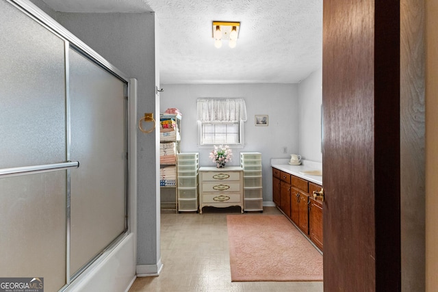 bathroom with enclosed tub / shower combo, a textured ceiling, vanity, and tile patterned floors