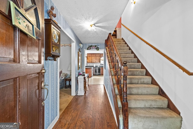 entryway featuring stairway, dark wood finished floors, and a textured ceiling