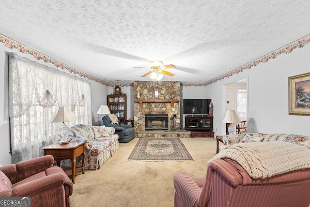 carpeted living room featuring a textured ceiling, ceiling fan, and a stone fireplace