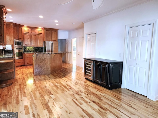 kitchen with wine cooler, a kitchen island, brown cabinets, stainless steel appliances, and a sink