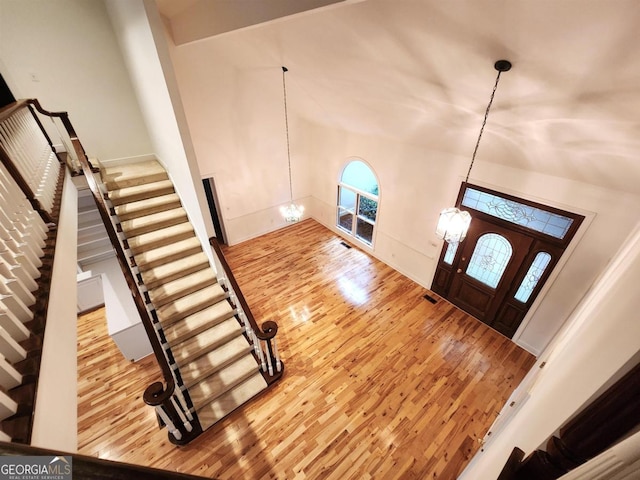 entryway with stairs, wood finished floors, visible vents, and an inviting chandelier