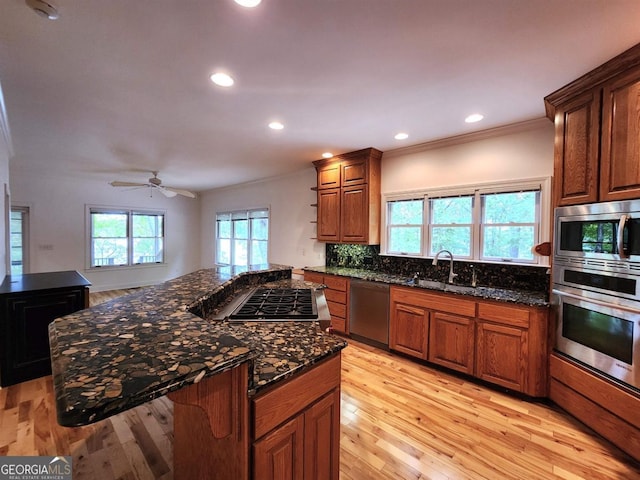 kitchen featuring appliances with stainless steel finishes, dark stone counters, a sink, and decorative backsplash