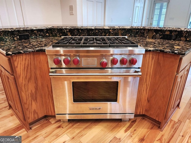 kitchen featuring brown cabinetry, luxury range, and light wood finished floors